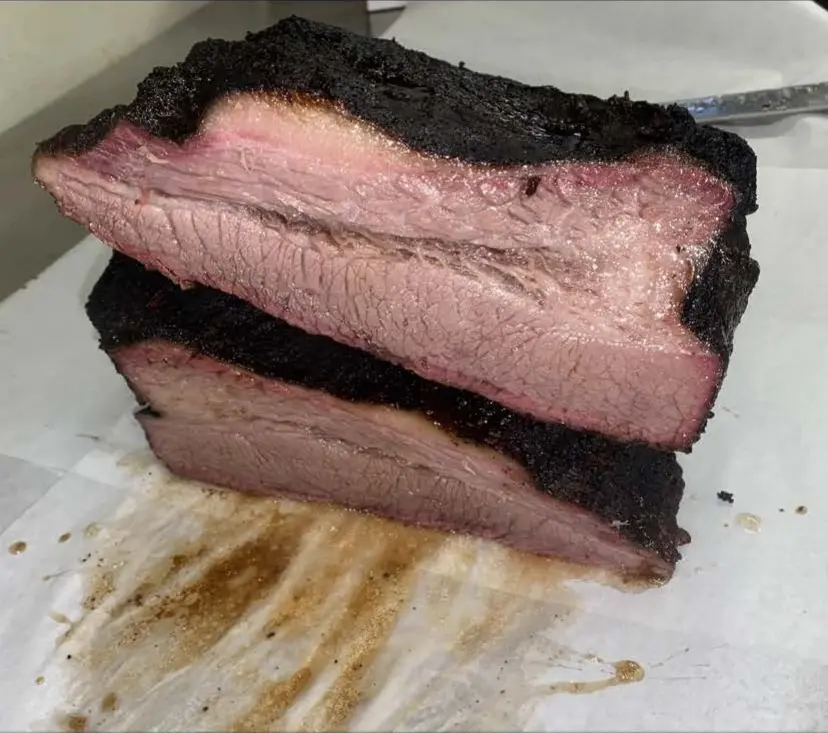 Thick-cut smoked brisket with a dark peppered bark and pink smoke ring