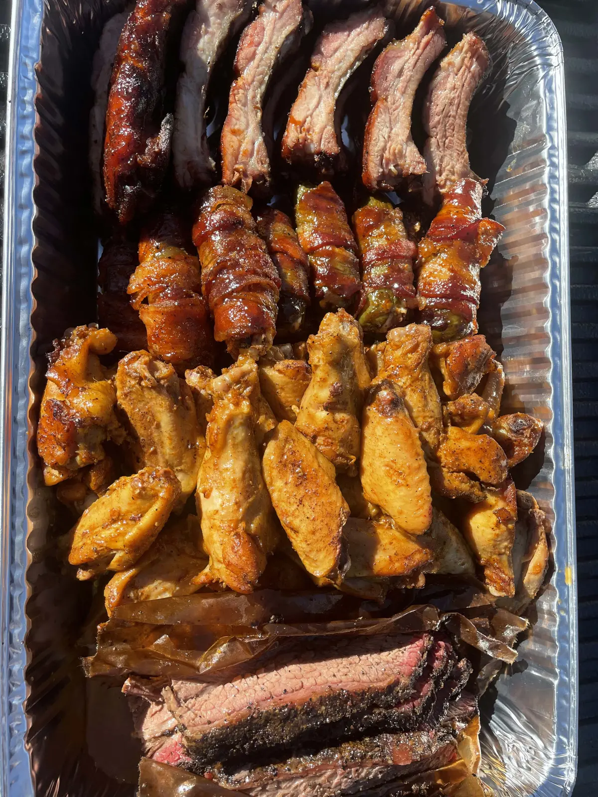 A full catering pan of ribs, wings and sliced brisket